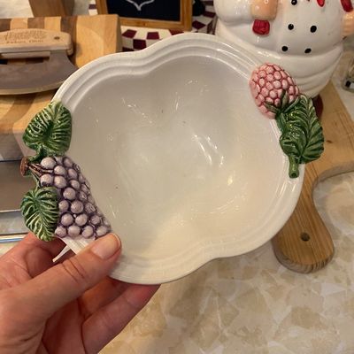 Sale Photo Thumbnail #49: Vintage ceramic fruit-themed serving bowl featuring raised grape and berry handle accents with visible fine crazing throughout.