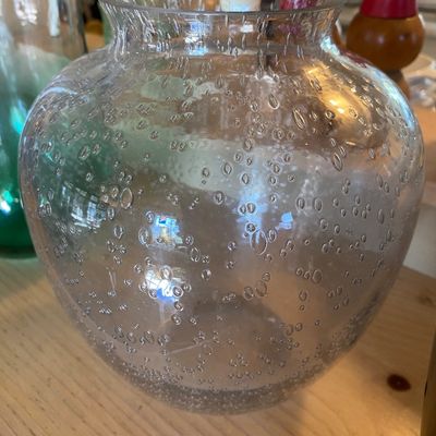 Sale Photo Thumbnail #97: Round clear controlled bubble glass vase sitting on a light wood surface.