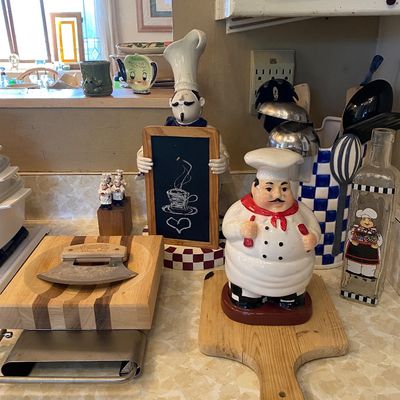 Sale Photo Thumbnail #10: Chef-themed kitchen decor collection, including a ceramic chef cookie jar, chef chalkboard figure, wooden cutting boards, and an oil bottle.