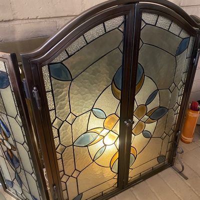 Sale Photo Thumbnail #36: Three-panel stained glass fireplace screen featuring an arched bronze-finished metal frame and stylized floral geometric patterns.