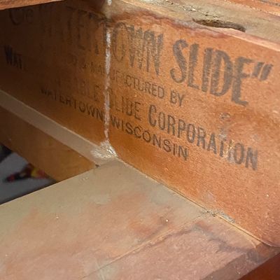 Sale Photo Thumbnail #192: Detail shot of the wooden underside mechanism of a vintage table, featuring a manufacturer stamp for "Watertown Slide" by the Watertown Table Slide Corporation.