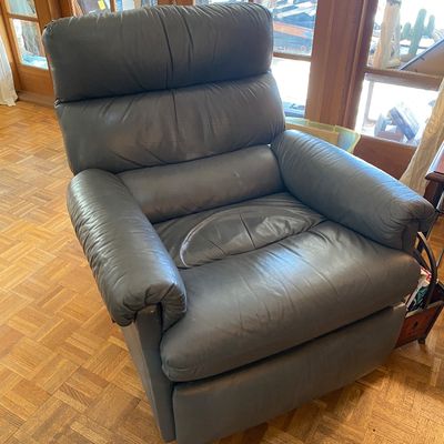 Sale Photo Thumbnail #187: Plush charcoal grey leather reclining armchair featuring padded arms and a segmented back cushion.