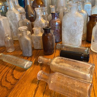 Sale Photo Thumbnail #52: Large collection of antique glass medicine bottles, apothecary jars, and flasks in clear, amber, and cobalt glass.