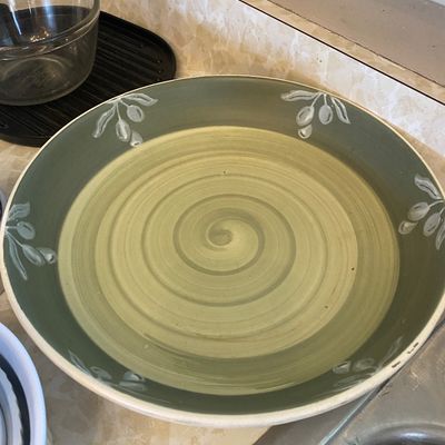 Sale Photo Thumbnail #42: Large ceramic serving bowl featuring a light olive green swirl center surrounded by a darker green rim with painted olive branch motifs.