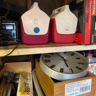 Sale Photo Thumbnail #109: Pair of vintage Igloo Playmate personal coolers and a boxed Craftsman router table sitting above a large silver-toned wall clock stored in a wooden crate.
