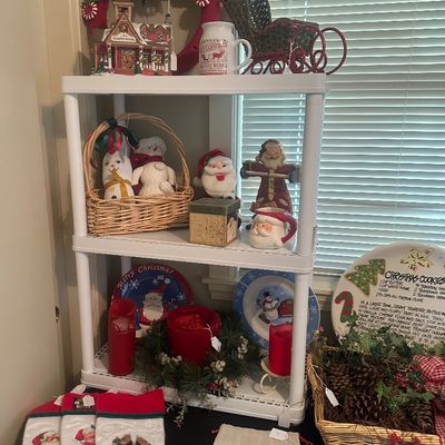 Sale Photo Thumbnail #51: Collection of holiday decorations, including embroidered Christmas stockings, Santa figurines, festive plates, candles, and a decorated plastic storage rack.