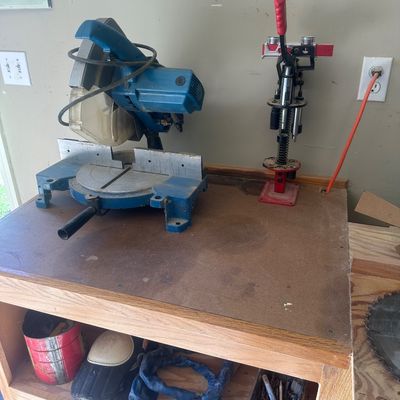 Sale Photo Thumbnail #20: Blue compound miter saw and a red reload press mounted on a wooden workshop table.