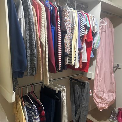 Sale Photo Thumbnail #61: Walk-in closet filled with organized women's clothing, including sweaters, shirts, pants, a pink garment bag, and rain boots.