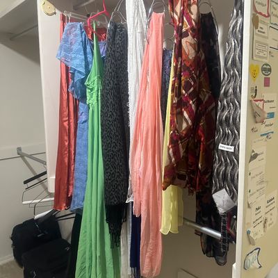 Sale Photo Thumbnail #59: Selection of women's dresses, scarves, and accessories hanging in a closet alongside luggage.