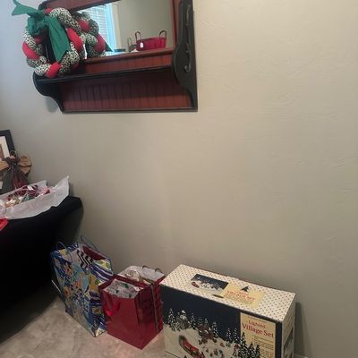 Sale Photo Thumbnail #53: Rustic red and black wooden wall mirror with a small shelf, paired with boxed holiday decor items and gift bags sitting below.