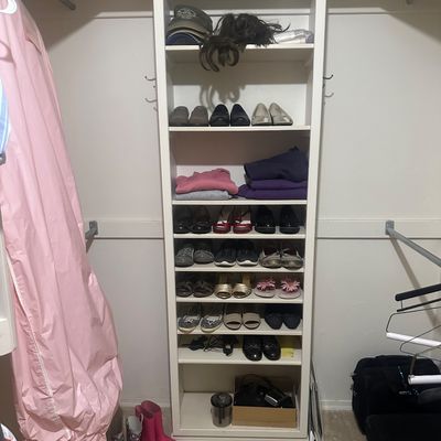 Sale Photo Thumbnail #58: A walk-in closet featuring a built-in white shelving unit filled with assorted women's shoes, folded garments, hats, and accessories, along with rain boots on the floor.