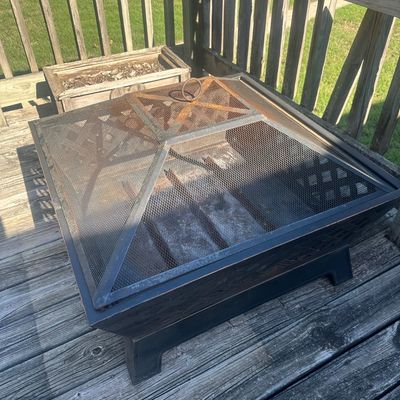 Sale Photo Thumbnail #22: Square black metal outdoor fire pit with mesh spark screen, showing surface rust from outdoor use.
