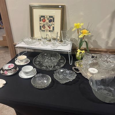 Sale Photo Thumbnail #40: Collection of glassware and china including cut crystal bowls, Irish coffee mugs, teacups with saucers, a silver-plated serving tray, and a framed fruit art print.