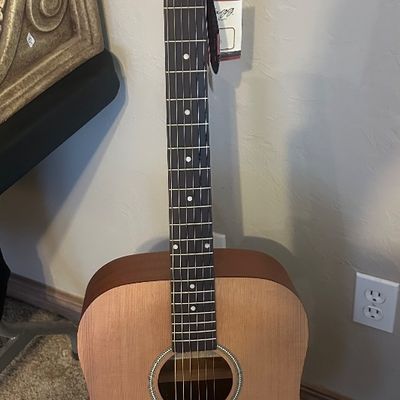 Sale Photo Thumbnail #30: Stagg acoustic dreadnought guitar with a natural finish soundboard, dark wood back and sides, and attached store tags.