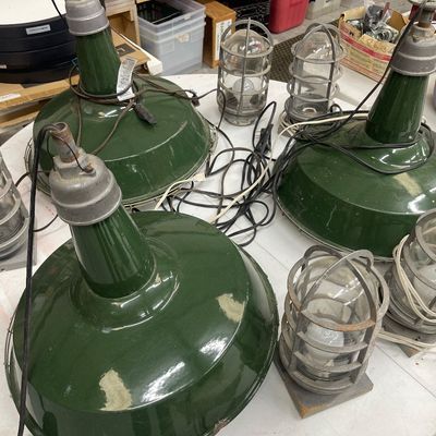 Sale Photo Thumbnail #59: Collection of vintage industrial lighting fixtures, including three green porcelain enamel pendant barn lights and several metal cage explosion-proof trouble lights.