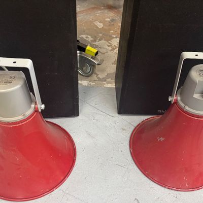 Sale Photo Thumbnail #46: Pair of vintage-style red and grey PA horn speakers with metal mounting brackets, sitting in front of two black floor speakers.