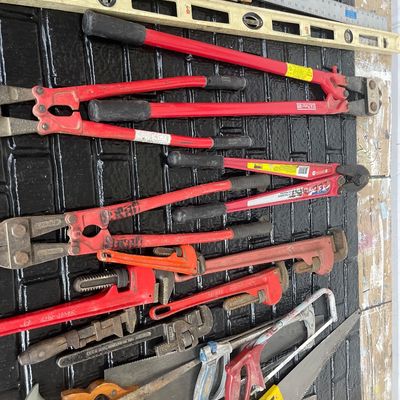 Sale Photo Thumbnail #55: Assortment of hand and shop tools, including heavy-duty bolt cutters, pipe wrenches, spirit levels, rulers, and hand saws in well-used condition.