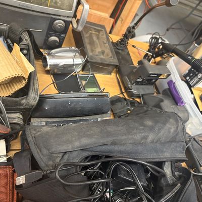 Sale Photo Thumbnail #5: Collection of vintage electronics, including a Radio Shack receiver, digital camcorder, Polaroid camera, microphones, and various cables packed in soft cases.