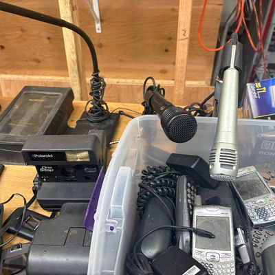 Sale Photo Thumbnail #3: Collection of vintage electronics, including a Polaroid OneStep instant camera, handheld microphones, and various late 1990s to 2000s cell phones and PDAs.