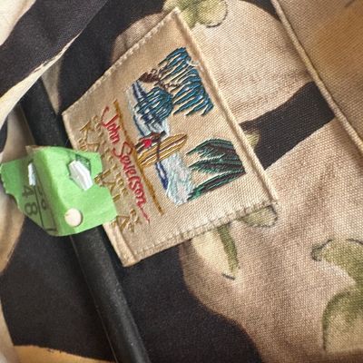Sale Photo Thumbnail #36: Vintage John Severson Collection Hawaiian shirt label featuring a surf scene, paired with a green pricing tag.