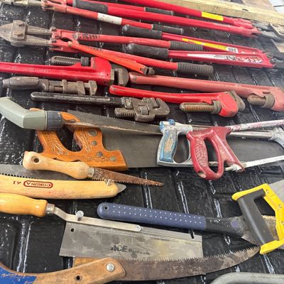Sale Photo Thumbnail #48: Assortment of vintage and modern hand tools, including heavy-duty bolt cutters, pipe wrenches, hand saws, hacksaws, and levels.