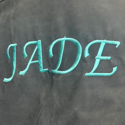 Sale Photo Thumbnail #29: Custom turquoise embroidery reading "JADE" on a black fabric background.