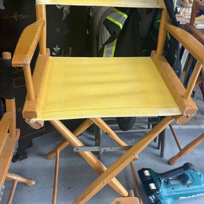 Sale Photo Thumbnail #53: Tall wooden director's chair with bright yellow canvas seat and backrest, featuring a built-in wooden footrest.