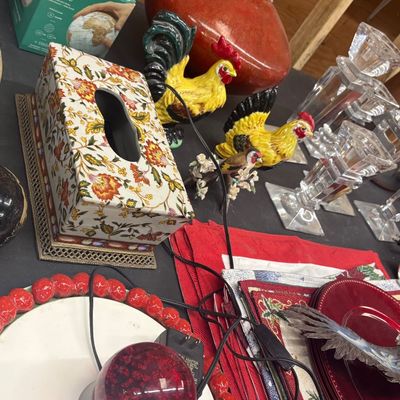 Sale Photo Thumbnail #12: Collection of tabletop decor including a floral tissue box cover, ceramic rooster figurines, glass candle holders, red linens, and globes.