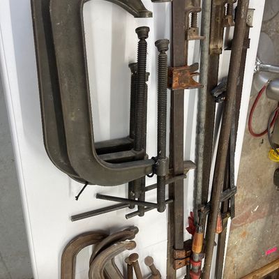 Sale Photo Thumbnail #61: Assortment of heavy-duty vintage woodworking clamps, including large C-clamps and long bar clamps, showing light rust and age-related wear.