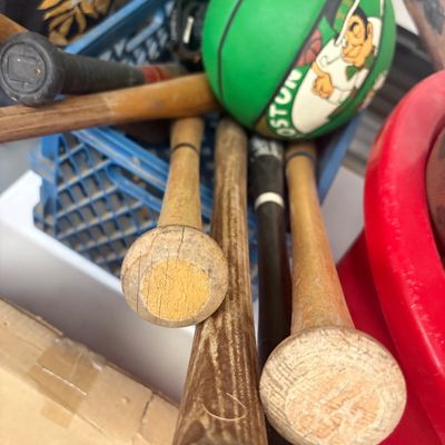 Sale Photo Thumbnail #25: Collection of vintage wooden and composite baseball bats stored in a blue plastic crate alongside a green Boston Celtics souvenir basketball.