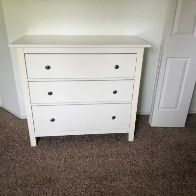 White three-drawer dresser featuring dark metal round knobs.