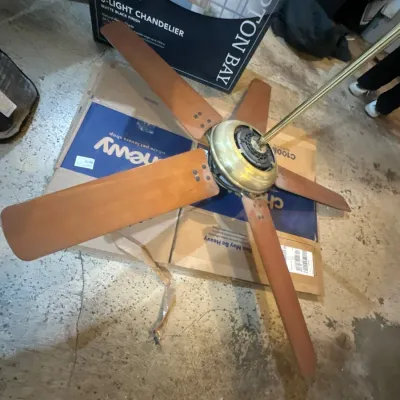 Five-blade ceiling fan with brass housing and natural wood-tone blades