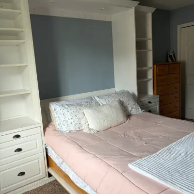 Modern white queen Murphy bed featuring integrated side shelving and lower drawers.