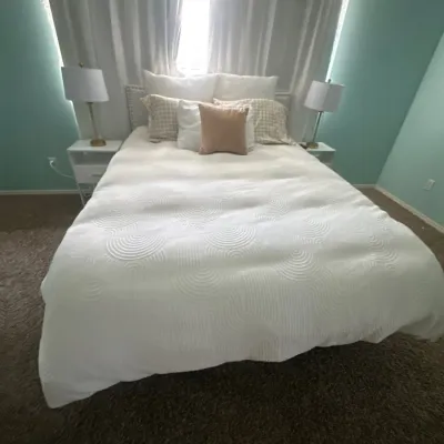 Bedroom set featuring a Sealy EASE adjustable queen size bed dressed in a textured white comforter with accent pillows, flanked by...