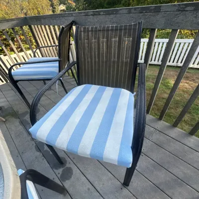 Outdoor patio armchairs with mesh backs, dark metal frames, and blue-and-white striped seat cushions.