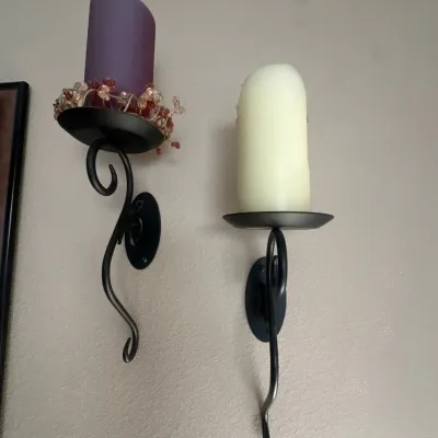 Pair of wrought iron wall sconce candle holders with curved stems, holding purple and cream pillar candles.