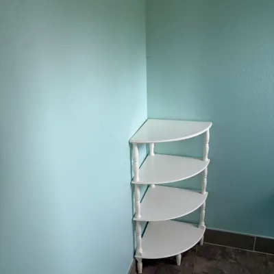 White four-tier corner etagere shelf with turned spindle supports.
