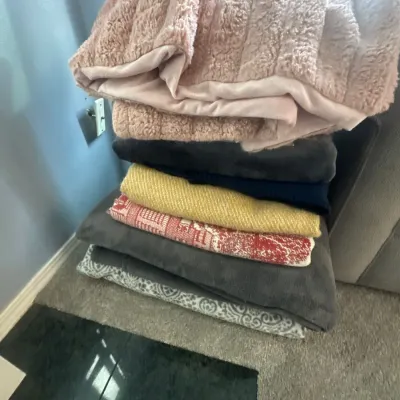 Stack of assorted contemporary throw blankets in various colors, textures, and patterns.