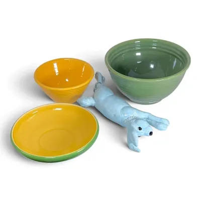 Sale Photo Thumbnail #221: Collection of colorful ceramic items, including yellow and sage green Bauer-style concentric ring mixing bowls, a shallow dish, and a whimsical light blue dog figurine.