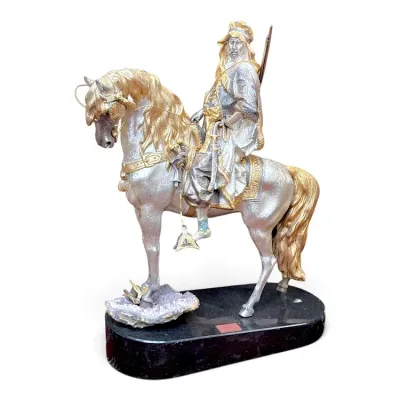 Sale Photo Thumbnail #196: Detailed silver and gold-toned equestrian statue of an Arabian rider, mounted on a dark stone base with amethyst mineral accents.