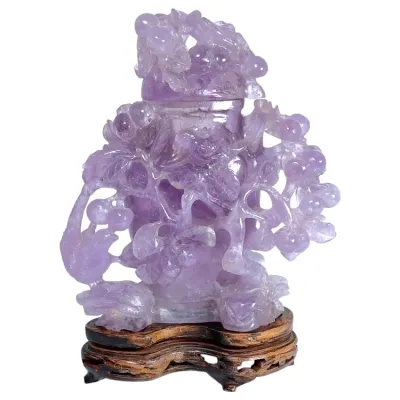 Sale Photo Thumbnail #165: Hand-carved Chinese amethyst quartz snuff bottle with lid, featuring intricate floral and grape vine motifs on a carved wooden display stand.