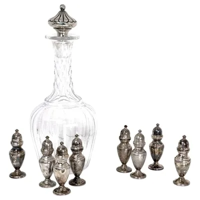 Sale Photo Thumbnail #163: Vintage cut glass decanter with a sterling silver top, accompanied by a set of eight matching tarnished silver salt and pepper shakers.