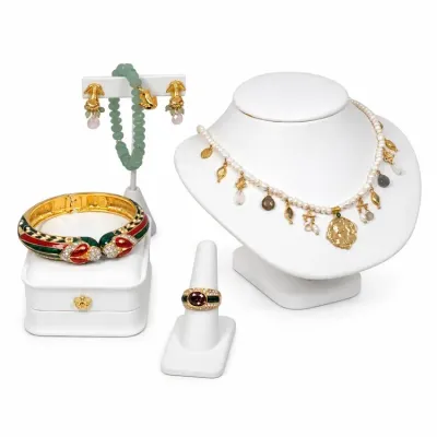 Sale Photo Thumbnail #13: Collection of fine designer jewelry featuring a pearl and charm necklace, an ornate red and green enamel hinged bangle, a garnet statement ring, a light green beaded bracelet, and matching clip-on earrings displayed on white stands.