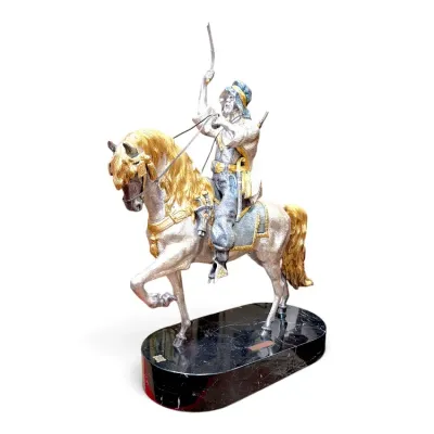 Sale Photo Thumbnail #195: Detailed silver- and gold-toned metal sculpture depicting an Arabian warrior on horseback, mounted on a polished black marble base.