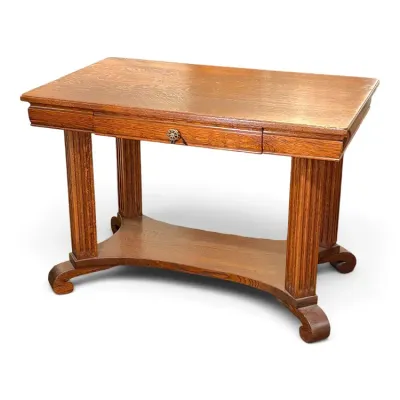 Sale Photo Thumbnail #130: Antique quarter-sawn oak library table featuring a single central drawer with a ornate knob, fluted column supports, and a curved stretcher base.