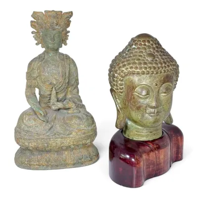 Sale Photo Thumbnail #232: Pair of Asian bronze Buddha figures, including a seated deity with an ornate headdress and a Buddha head sculpture mounted on a polished wood base.