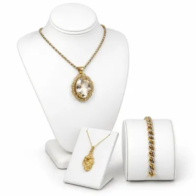 Sale Photo Thumbnail #14: Three-piece jewelry selection displayed on white leatherette stands, featuring a large oval crystal pendant necklace, a gold nugget pendant necklace, and a two-tone curb link bracelet.