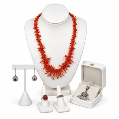 Sale Photo Thumbnail #9: Collection of red coral jewelry including a branch coral strand necklace, two sterling silver and coral rings, dangle earrings, and a decorative pendant in a display box.