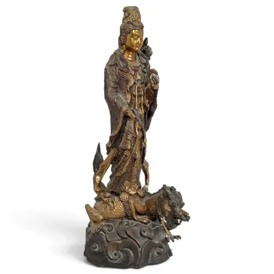 Sale Photo Thumbnail #168: Gilt and dark patinated bronze statue of Guanyin standing atop a dragon and cloud base, featuring intricate robes and flowing ribbons.