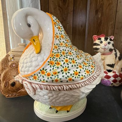 Sale Photo Thumbnail #33: Vintage ceramic goose cookie jar wearing a floral bonnet, displayed alongside a bear honey pot and a cat cookie jar.